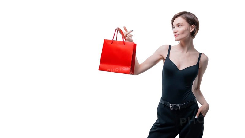 Portrait of stylish adult woman posing in studio on white background with red gift bag. Valentine's Day concept. Holidays and gifts