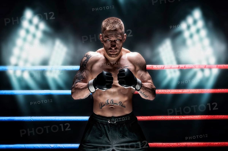 Mixed martial artist posing in the ring against spotlights. Concept of mma