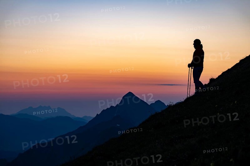 Mountaineer on mountain ridge with Rothorn peak in the background at blue hour