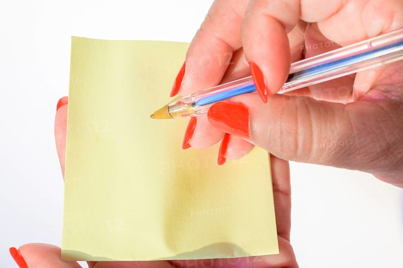 Woman's hand with painted nails holding blank letter paper on pure white background