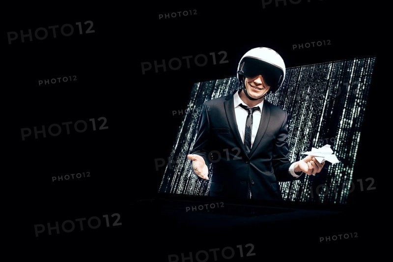 Portrait of a man in a suit and helmet. He launches a paper airplane from a laptop screen. Web Design Concept.