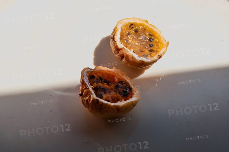 Juicy cut halves of a passion fruit with visible seeds in the sunlight