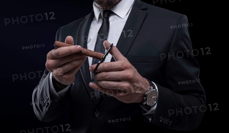 Image of an adult stylish man in a suit with a cigar. Cigar clubs concept.
