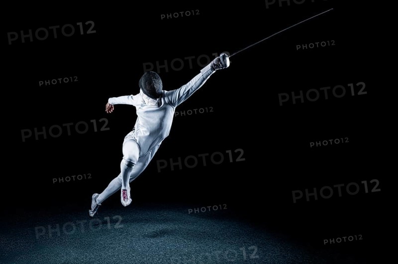 The fencer moves forward with a sword in his hand. Sport concept.