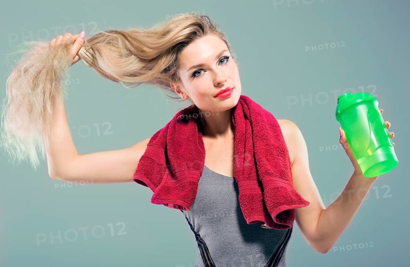 Charming model posing in the studio with a shaker in her hands and a towel around her neck.