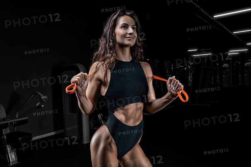 Tall athletic woman posing with gymnastic elastic bands in the gym. Fitness and bodybuilding concept.