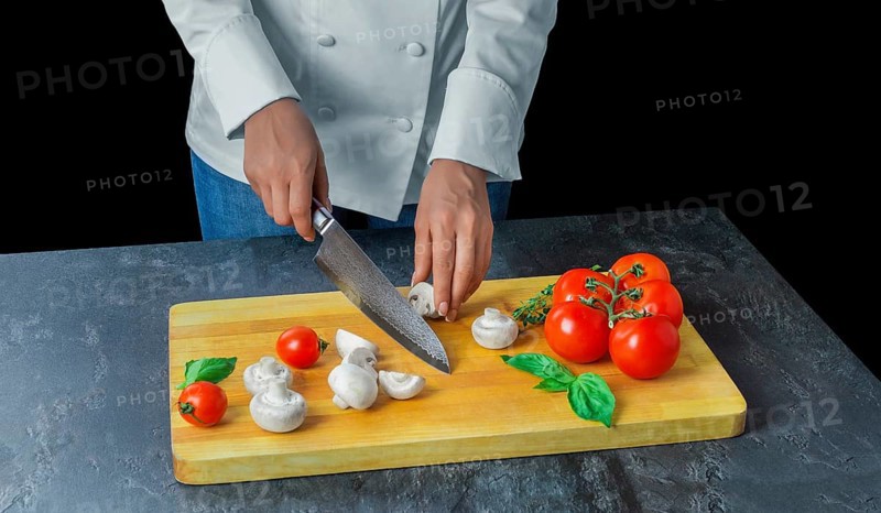 Professional chef cuts vegetables with a sharp knife from Damascus steel.
