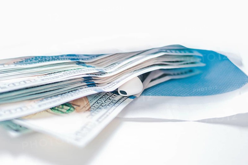 Pack of hundred-dollar bills along with a bug lie in an envelope. The concept of bribery and corruption.