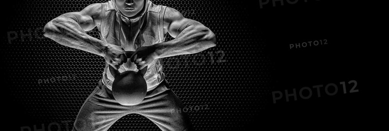 Portrait of an athlete pulling a kettlebell to his chin. The concept of sport and healthy lifestyle.