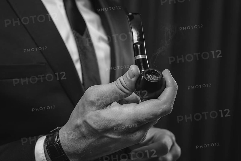 Image of male hands holding a smoking pipe. Tobacco smoking concept.