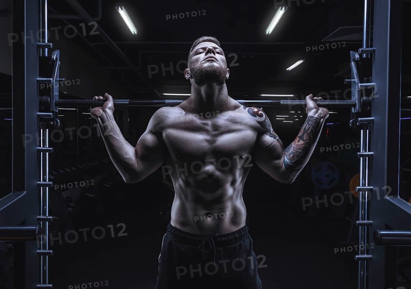 Portrait of an athlete with a barbell on the shoulders of the gym. Bodybuilding and fitness concept.