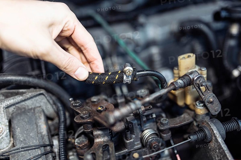Auto mechanic regulates fuel supply with throttle cable lever