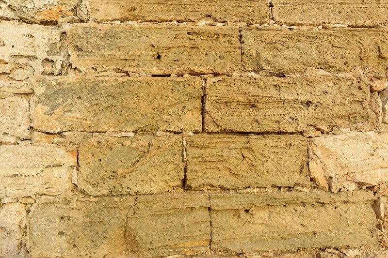 Close-up of a textured stone wall with varying beige tones and rough surface