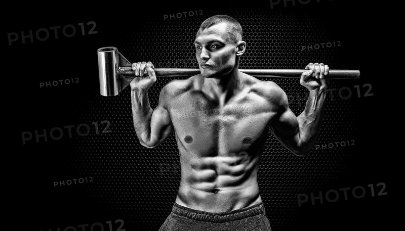 Portrait of an athlete with a sledgehammer on his shoulders. The concept of sport and healthy lifestyle.