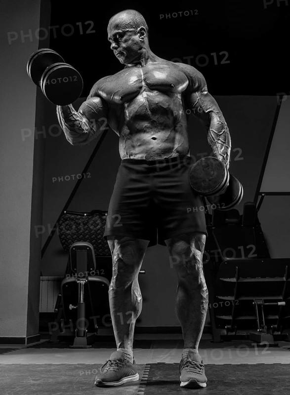 Professional weightlifter is training in the gym. Dumbbell Curl. Bodybuilding concept.