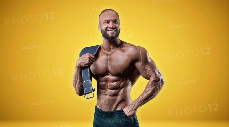 Isolated professional sportsman on a yellow background. Bodybuilding concept. Panorama. Advertising of a gym and sports nutrition.
