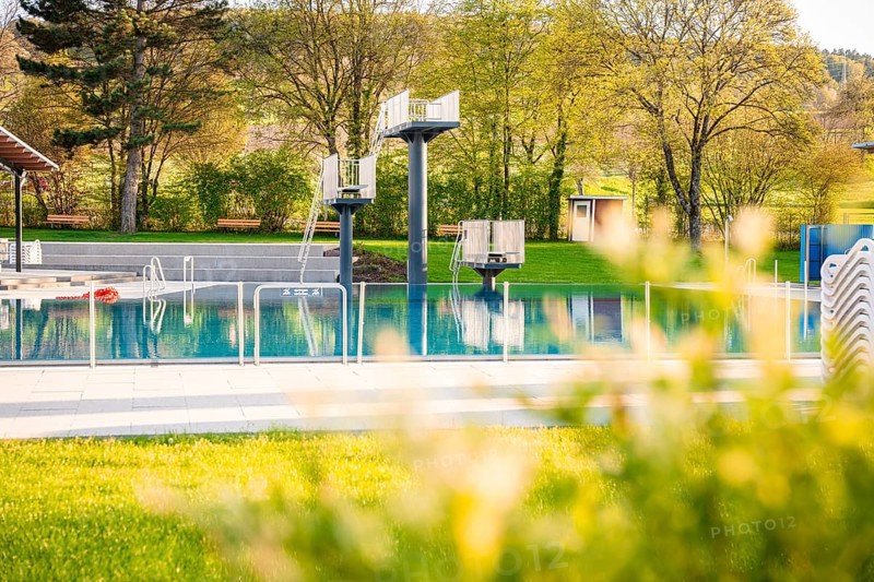 Competition pool in an outdoor pool with starting blocks and surrounded by trees in spring