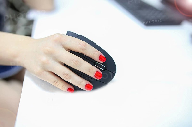 Girl's hand uses a vertical ergonomic joystick of a computer mouse. working at the computer