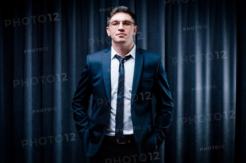 Adult man is standing in a suit against a black curtain. Business concept. The administrative staff of the company.