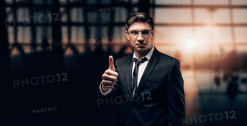 Portrait of a man in a business suit. He is standing at the airport with his finger raised. Ok sign. VIP transportation. Private airlines. Charter flights.