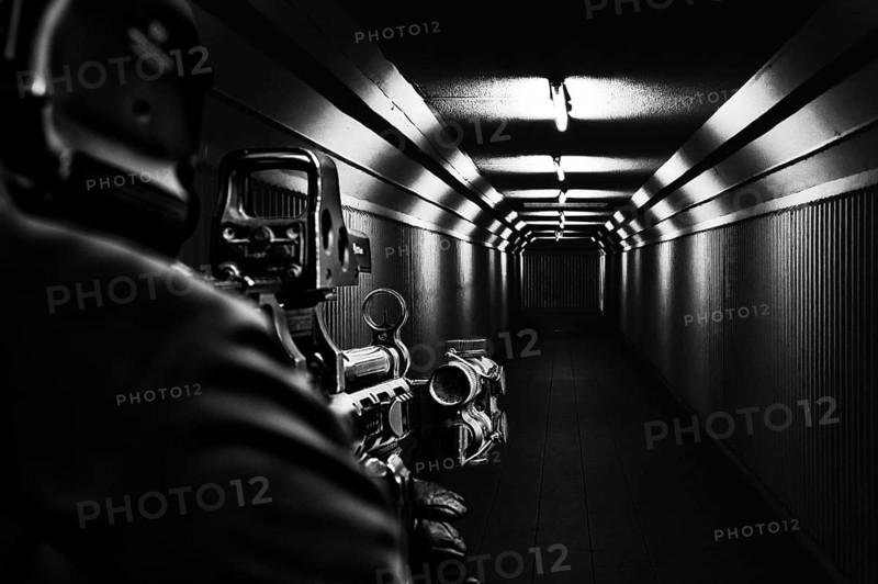 Computer player is standing in the hallway and is aiming at a collimator scope.