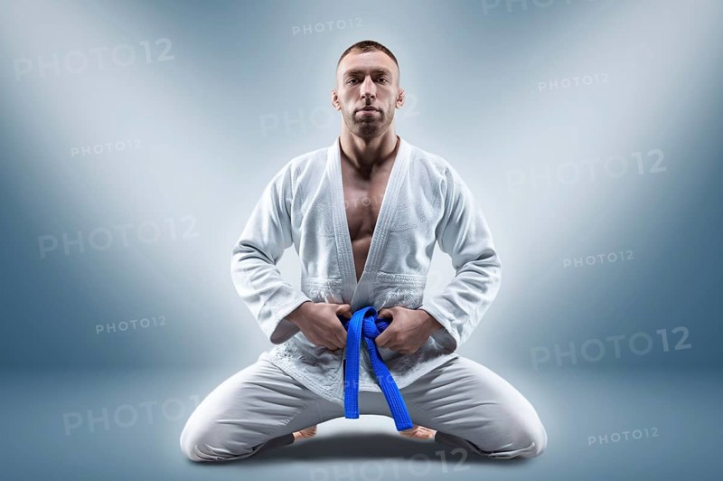 Athlete in a kimono with a blue belt sits and waits for the opponent. Concept of karate