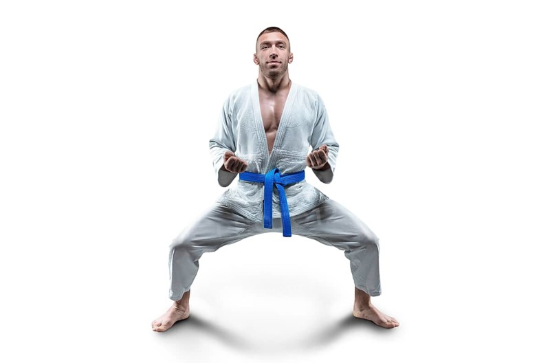 Athlete in a kimono with a blue belt stands in a fighting position. Concept of karate