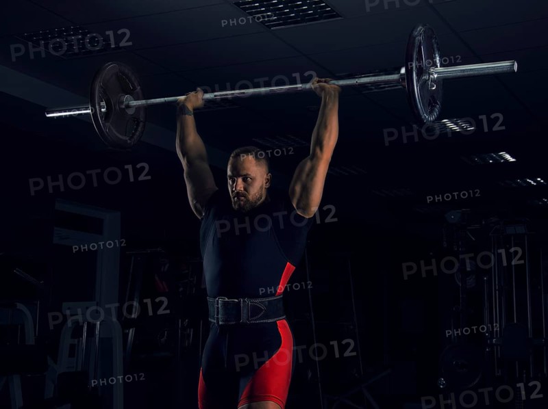 Weightlifter lifts the bar above his head. Strength training with a huge weight