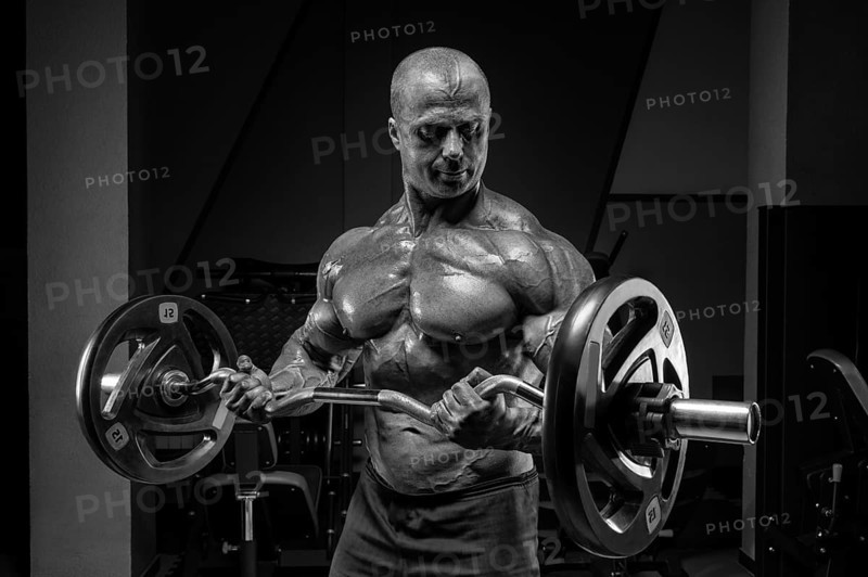 Professional weightlifter posing in the gym with a barbell in his hands. Classic bodybuilding.