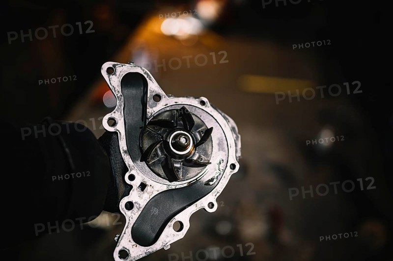 Automotive water pump of the engine cooling system in the hands of an auto mechanic