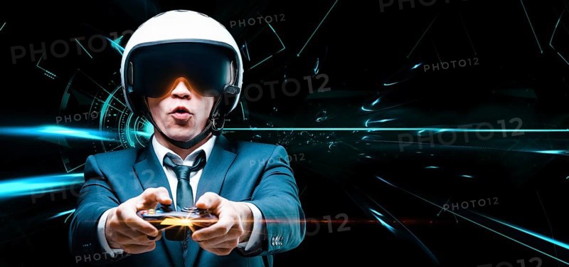 Portrait of a man in a suit and helmet of a pilot with a joystick in his hands. He enthusiastically plays a computer game. Game space. Game concept.