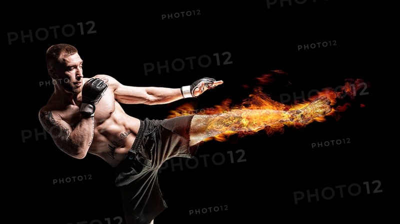 Kickboxer posing in the ring. Middle Kick with a burning foot. The concept of mma