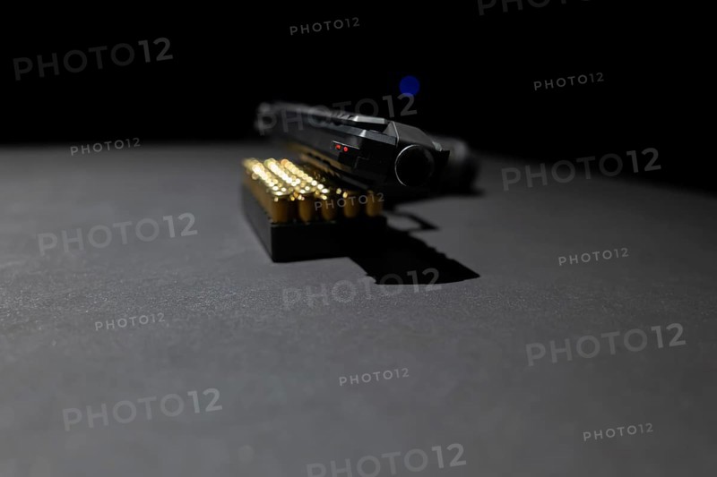 Modern Elegant Handgun Leaning on Munition Bullet on Grey Background in Switzerland