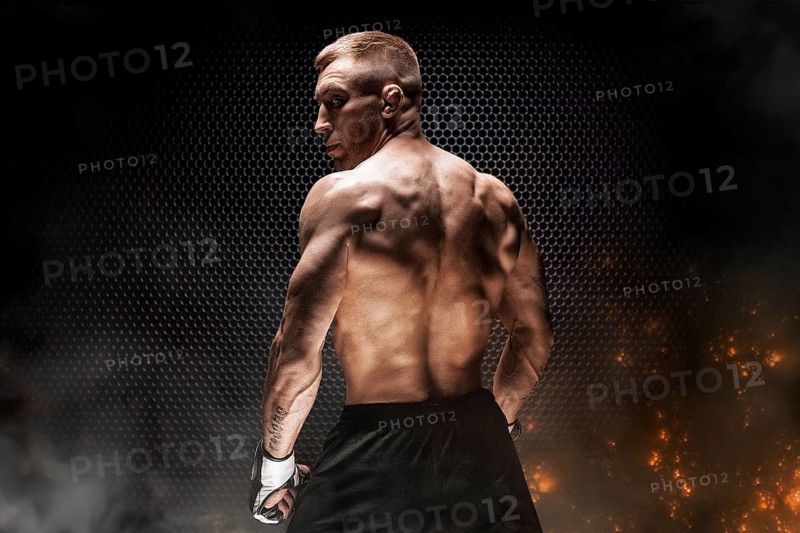 Kickboxer portrait on steel grid background. Back view. The concept of sports and mixed martial arts.