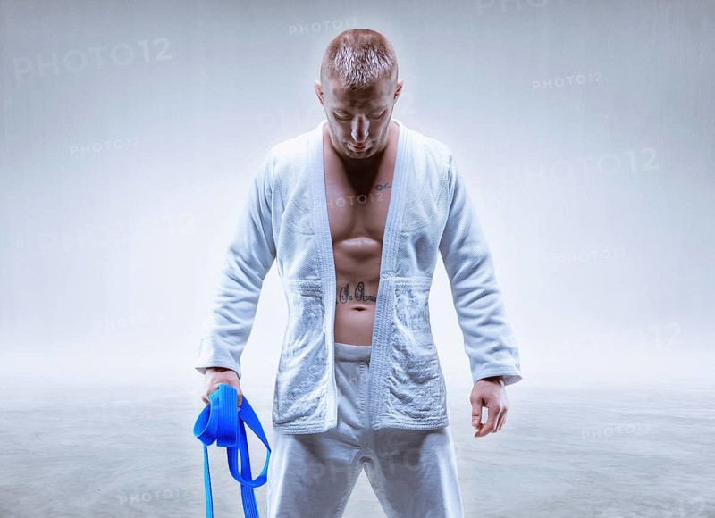 Athlete in a kimono with a blue belt stands with his head down. The concept of karate and judo.