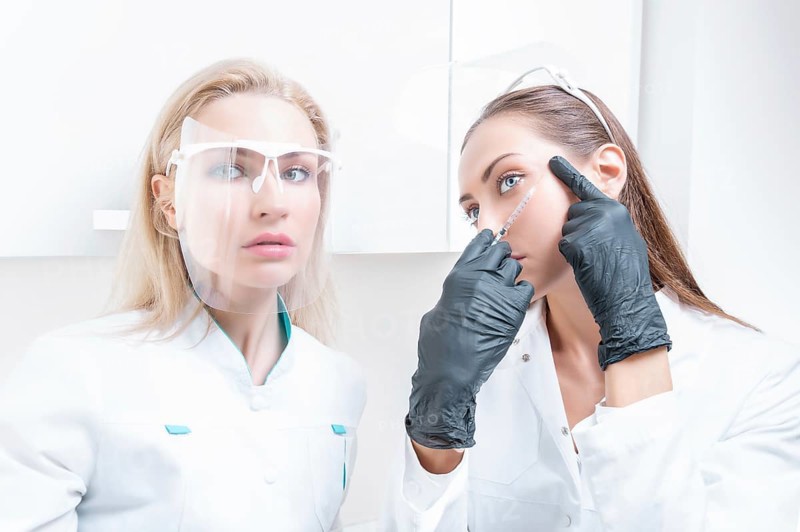 Portrait of the beautician and patient. The doctor injects botox. Skin rejuvenation and lifting concept.