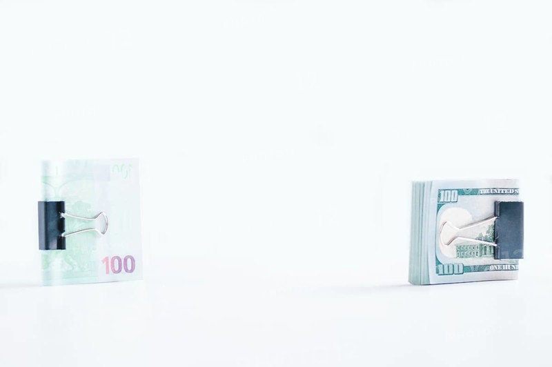 Packs of euros and hundred-dollar bills lie on a white table fastened with paperclips. The concept of savings during the crisis. Dollars vs Euros.