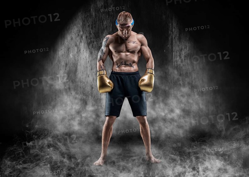 Professional wrestler is standing in the smoke in a dark place. Mixed martial arts