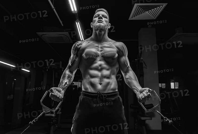 Portrait of an athlete pumping biceps in a crossover. Bodybuilding and fitness concept.