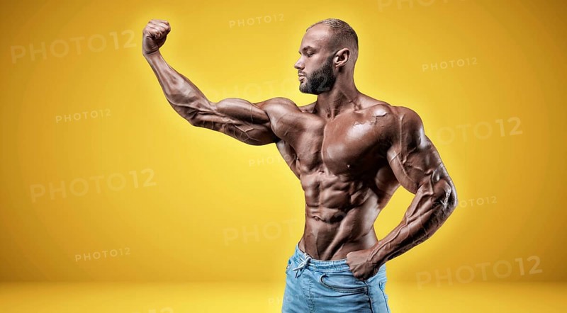 Isolated professional sportsman on a yellow background. Bodybuilding concept. Panorama. Advertising of a gym and sports nutrition.