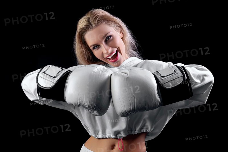 Cheerful and charming girl in a white sweatshirt poses with huge white gloves. The concept of sports