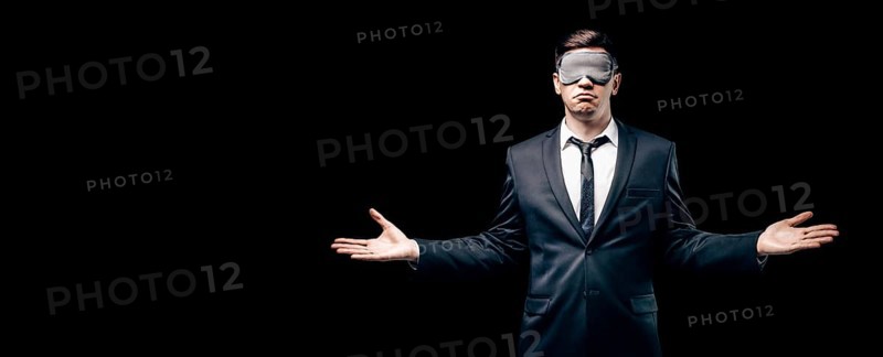 Portrait of a man in a mask for sleeping. He stands against a black wall. Blind business concept. Work during the crisis.