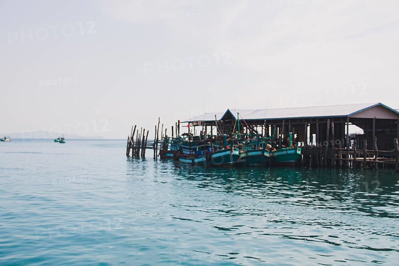 Fishing boats moored at a wooden pier in a serene waterfront village. Koh Sdach Island