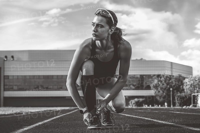Image of an athlete tying her shoelaces with spikes. Running concept.