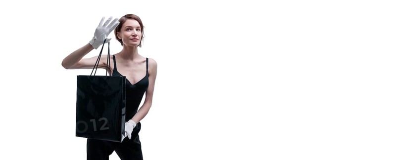 Stylish tall girl in white gloves demonstrates a black luxury package. The concept of safe shopping during a pandemic