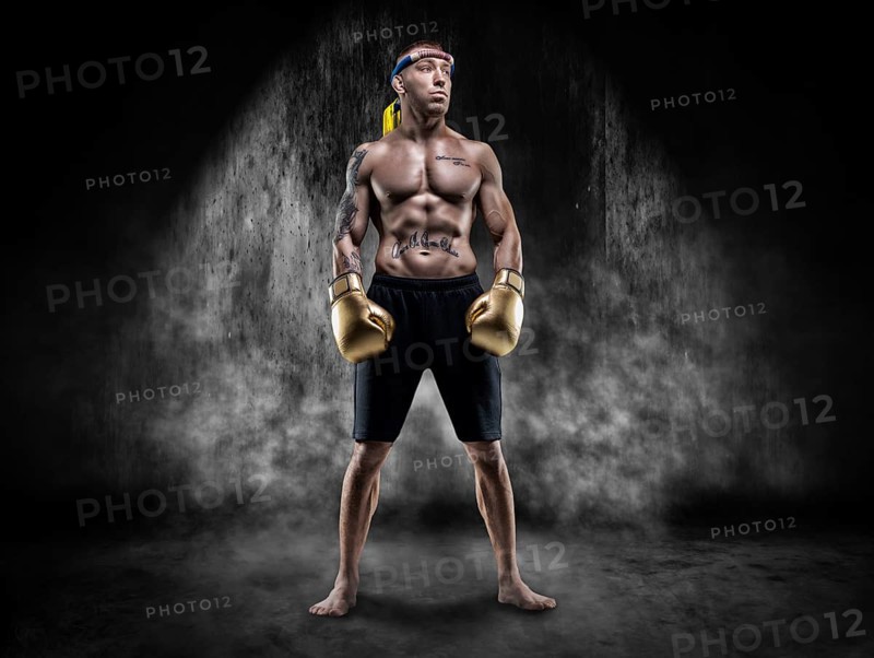 Professional wrestler is standing in the smoke in a dark place. Mixed martial arts