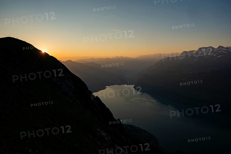 Mountain ridge with mountaineers and Swiss mountains and Lake Thun in the background at sunrise