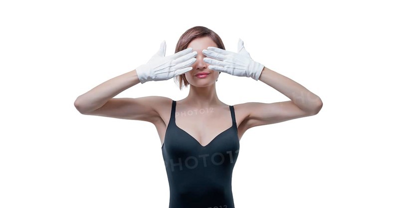 Beautiful young woman in white gloves covered her eyes with her hands