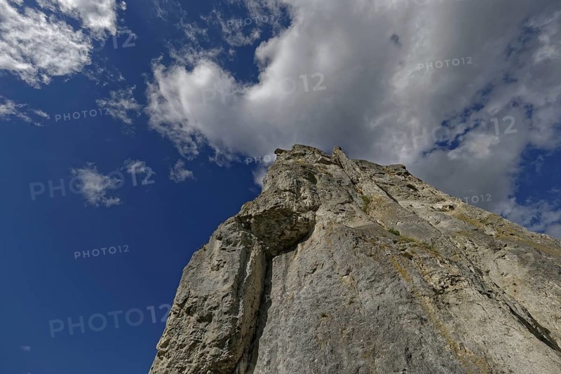 Striking limestone rock formation Burgstein with blue and white sky in the upper Altmuehltal surrounded by green vegetation