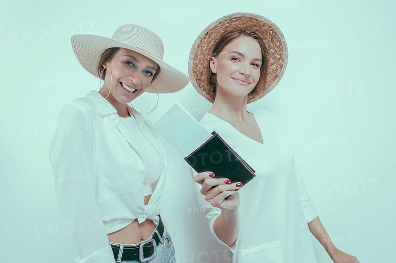 Portrait of two smiling women with passports and boarding passes in their hands. Travel concept.